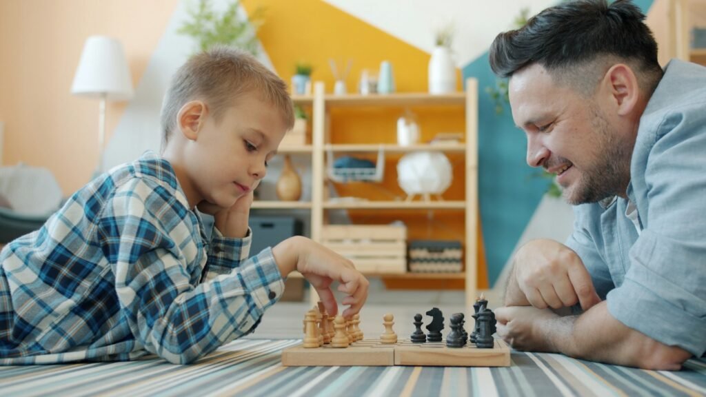 A parent and child playing chess together on the floor at home