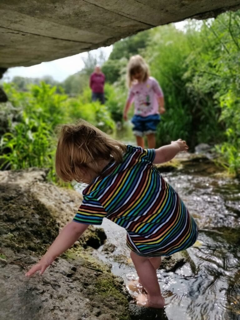 Two children walking through a shallow stream while exploring nature